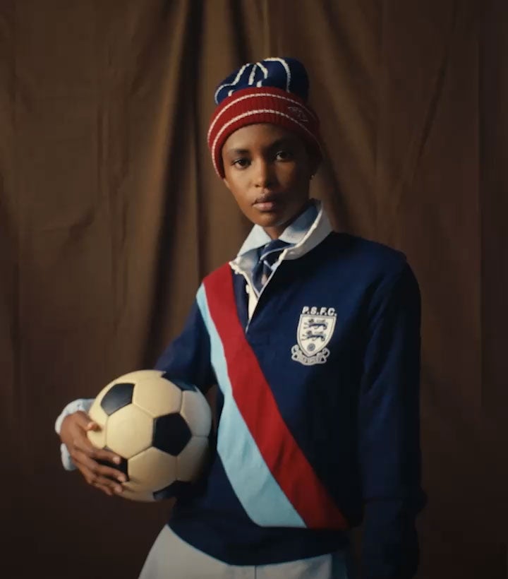 Woman wears navy blue Polo Sport shirt with blue-and-red diagonal stripe and blue-and-red beanie.