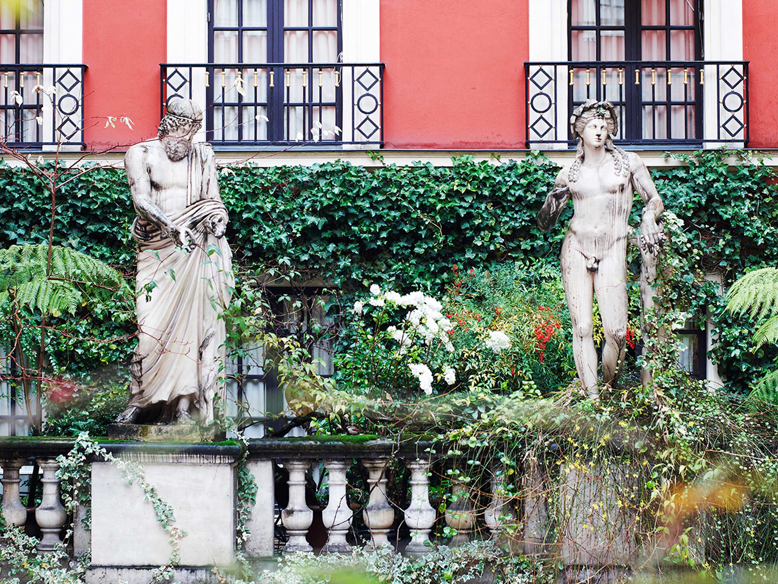 The interior courtyard of H<span>&ocirc;</span>tel Costes in Paris features sprawling ivy and large statues